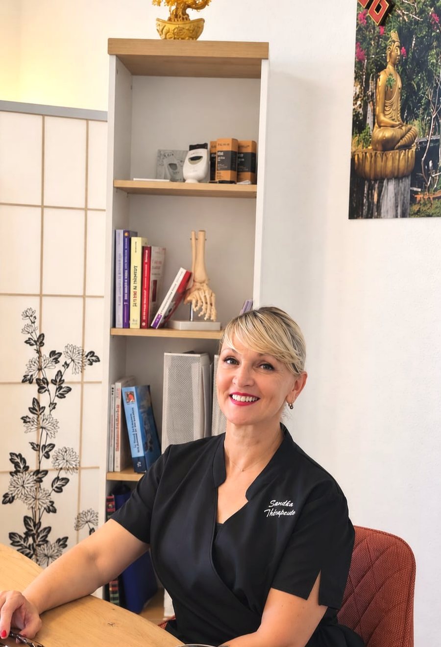 Sandka, thérapeute, dans son cabinet devant ses planches de réflexologie